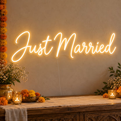Just Married Neon Sign on clear cut-to-shape acrylic, illuminated on a wall in a styled celebration setting