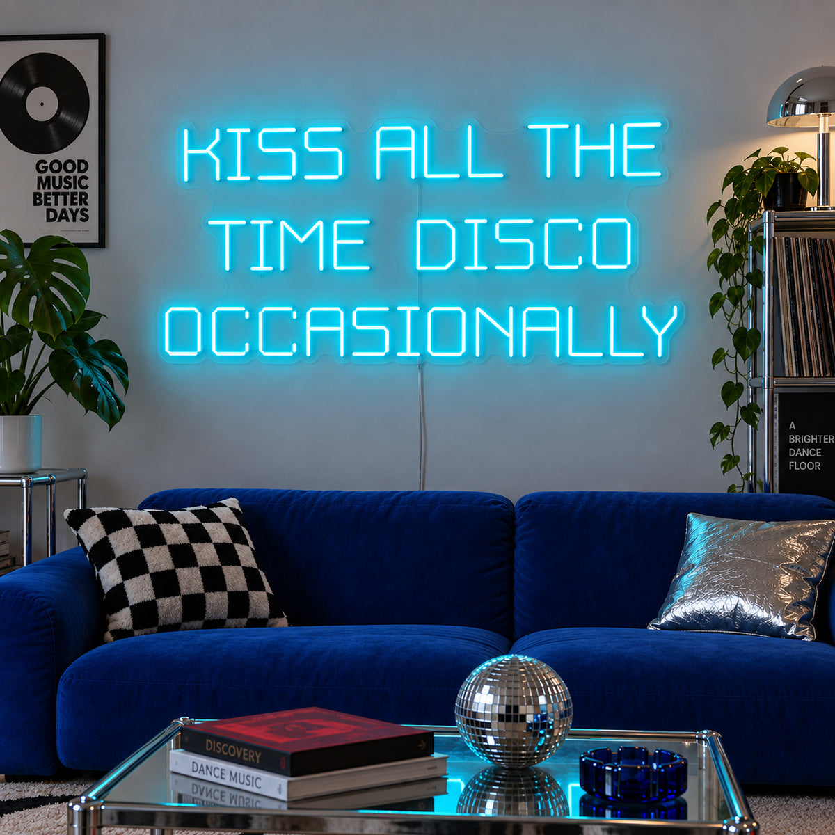 Ice Blue version of the Kiss All The Time Disco Occasionally Neon Sign, shown above a blue sofa near a disco ball.
