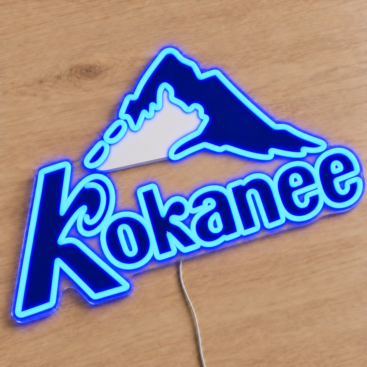 Kokanee neon sign with uniform blue neon outlines and white mountain print, first angle