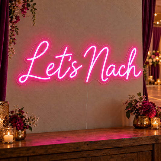 Let’s Nach Neon Sign on clear cut-to-shape acrylic, illuminated on a wall in a styled celebration setting