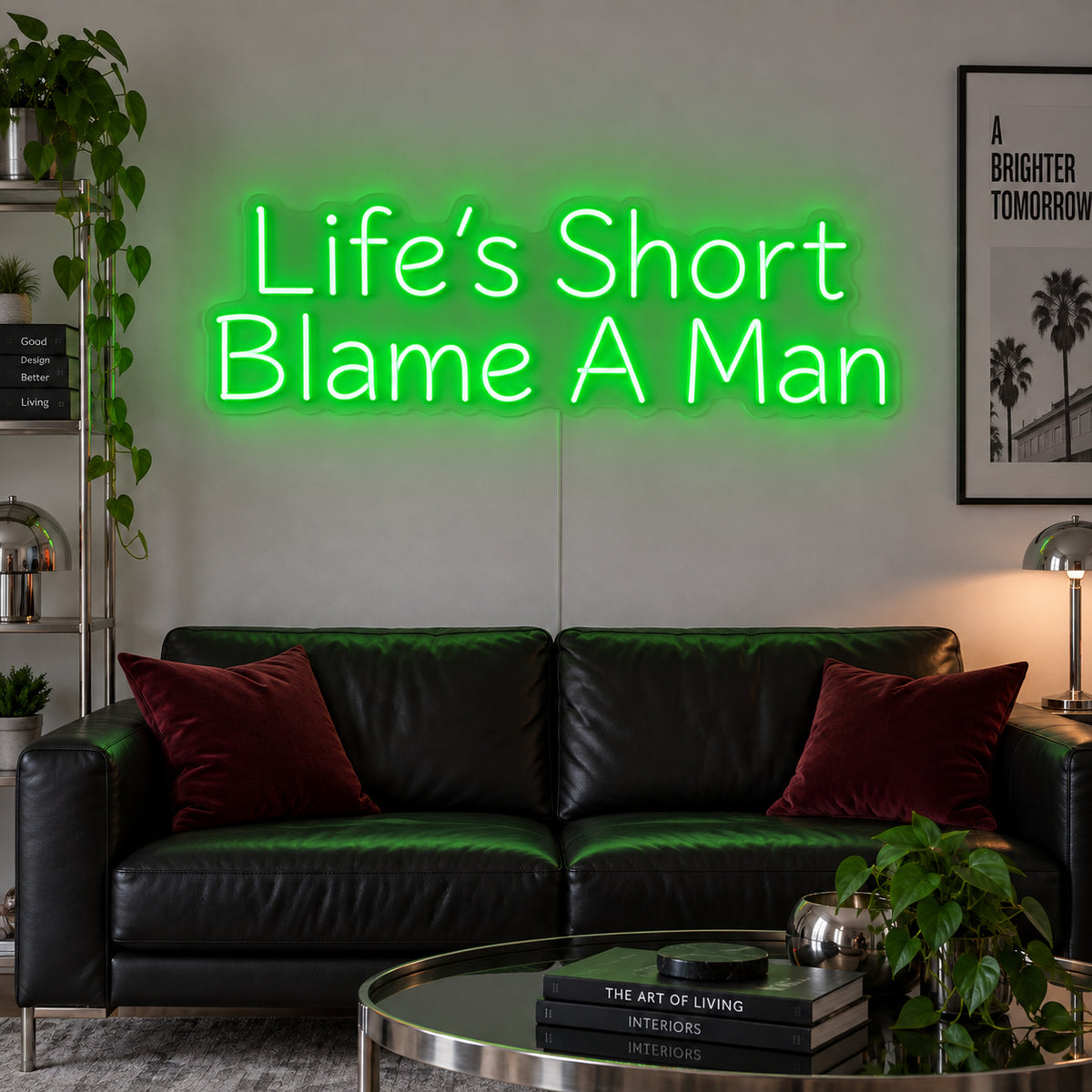 Life's Short Blame A Man Neon Sign with green lighting, displayed above a black leather sofa.