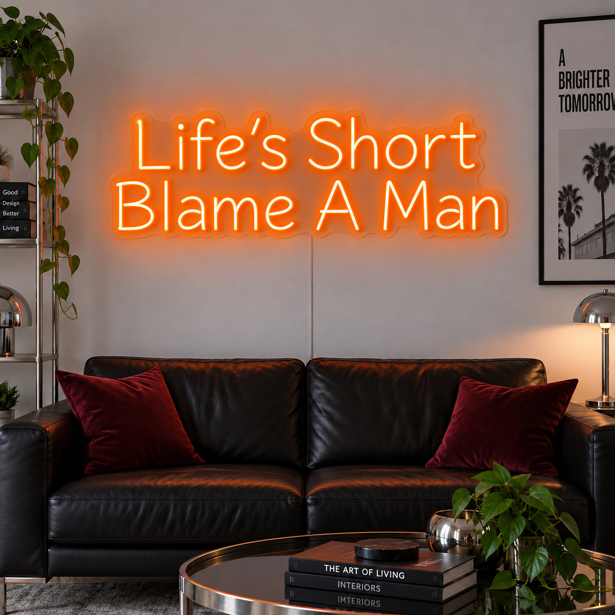Orange version of the Life's Short Blame A Man Neon Sign, shown above a black leather sofa.