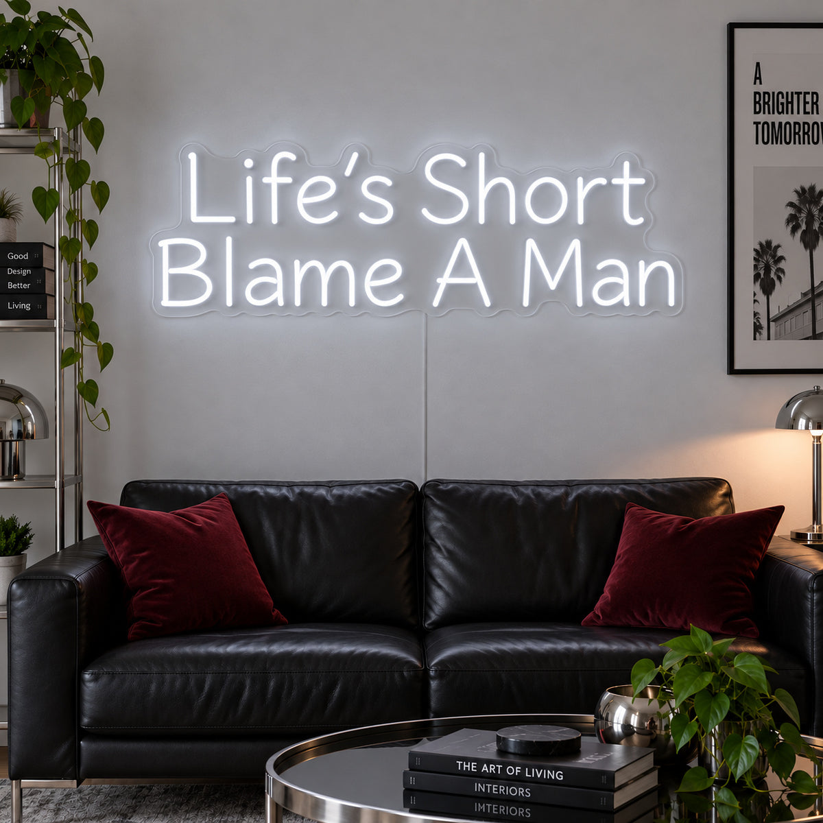 Life's Short Blame A Man Neon Sign, RGB colour-changing option shown in white above a black leather sofa.