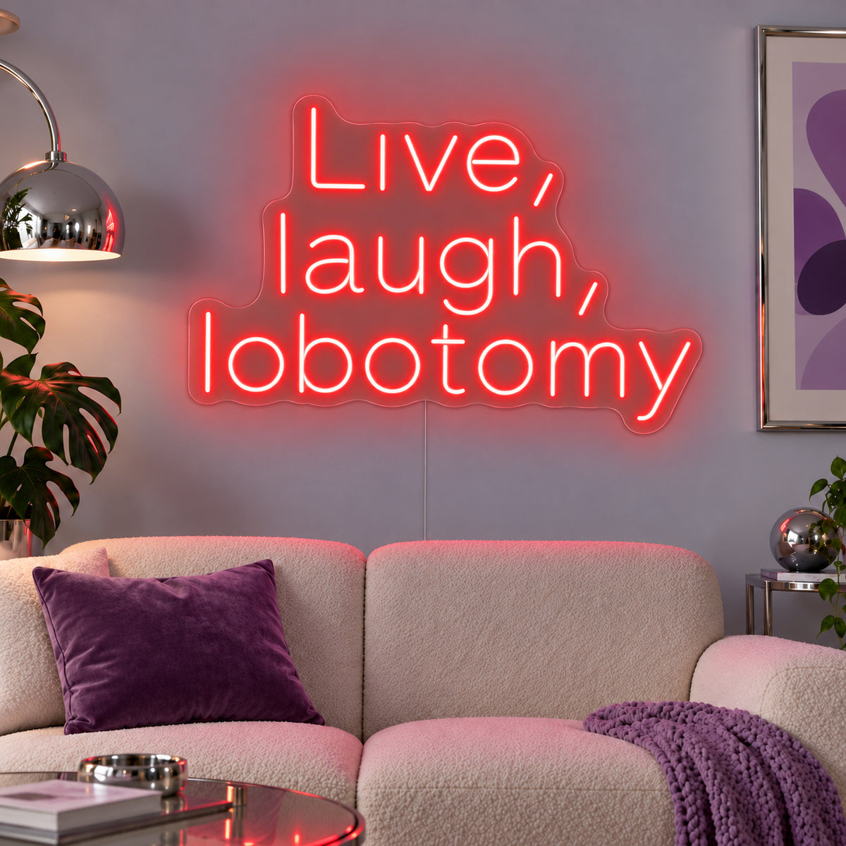 Live, Laugh, Lobotomy Neon Sign with red lighting, displayed above a cream sofa with purple cushions.
