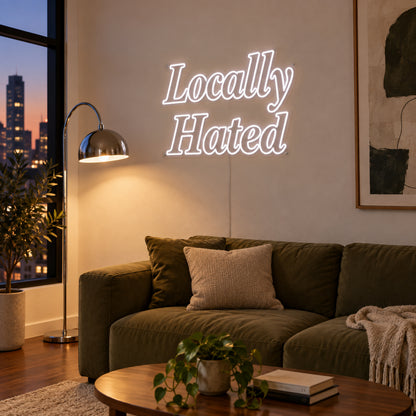 Locally Hated Neon Sign in white, featuring two lines of decorative Locally Hated lettering above a green sofa.