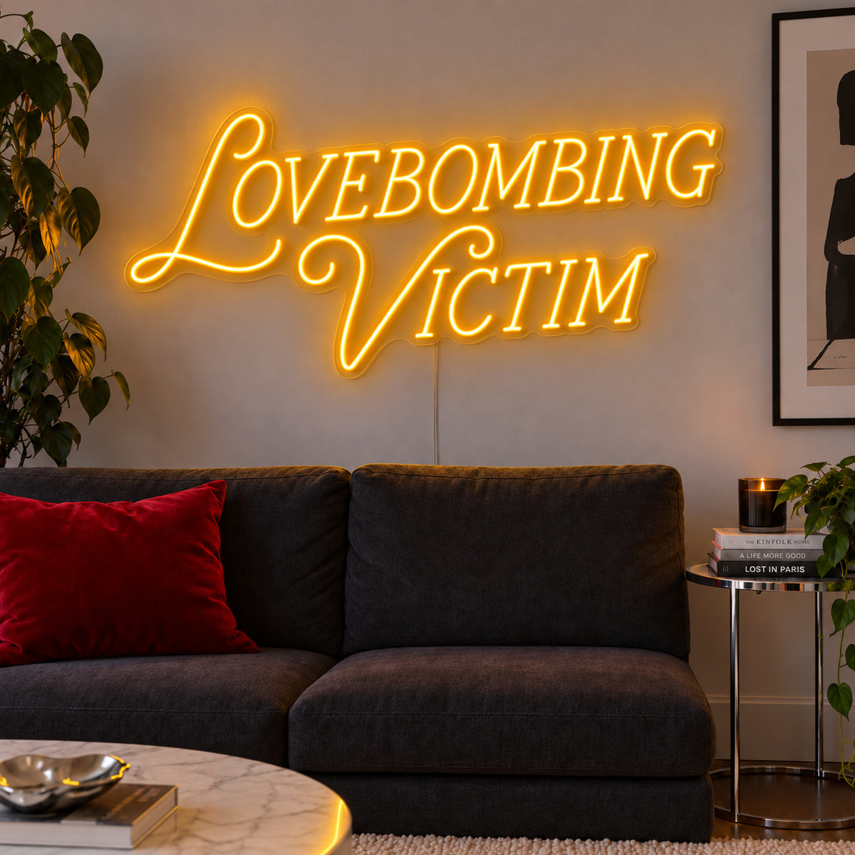 Lovebombing Victim Neon Sign glowing gold above a dark sofa with red cushions.