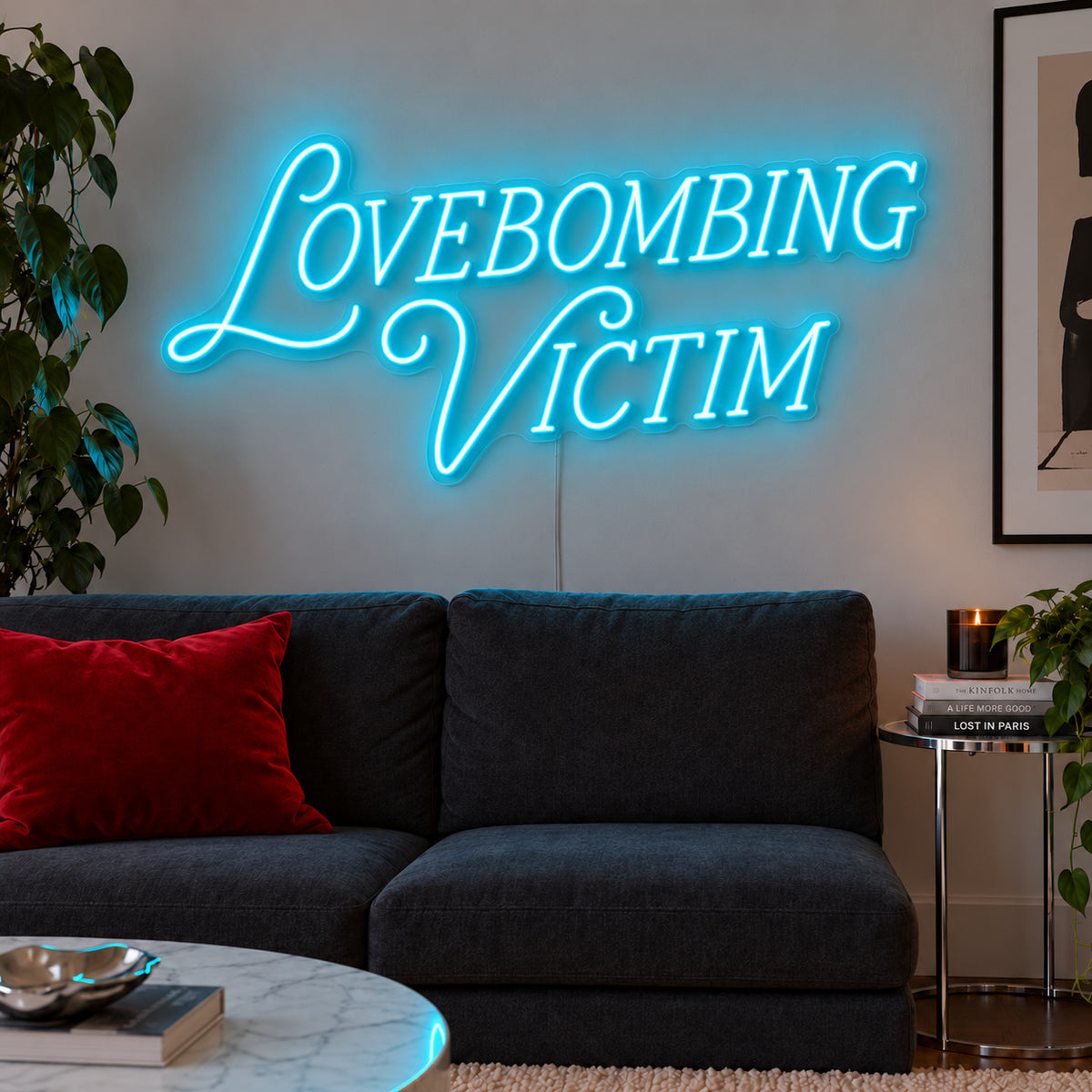 Ice Blue version of the Lovebombing Victim Neon Sign, shown above a dark sofa with red cushions.