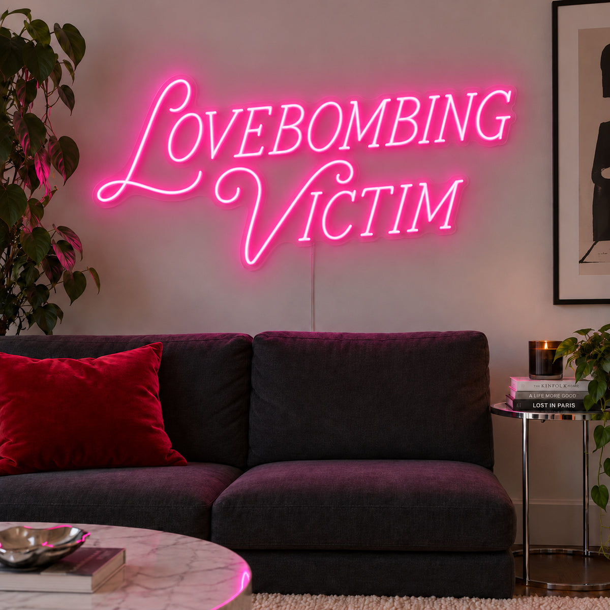 Lovebombing Victim Neon Sign glowing pink above a dark sofa with red cushions.