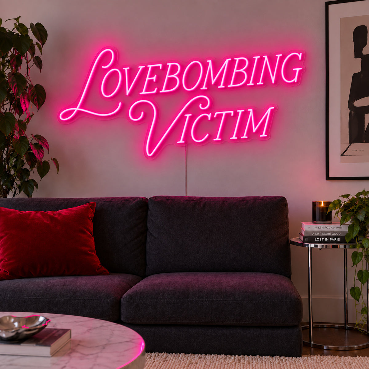 Rose Red version of the Lovebombing Victim Neon Sign, shown above a dark sofa with red cushions.