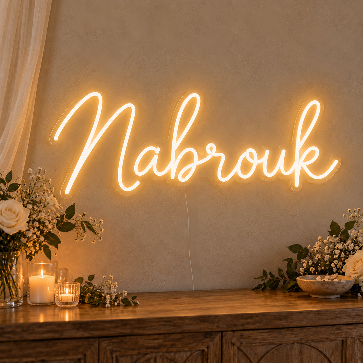 Mabrouk Neon Sign on clear cut-to-shape acrylic, illuminated on a wall in a styled celebration setting