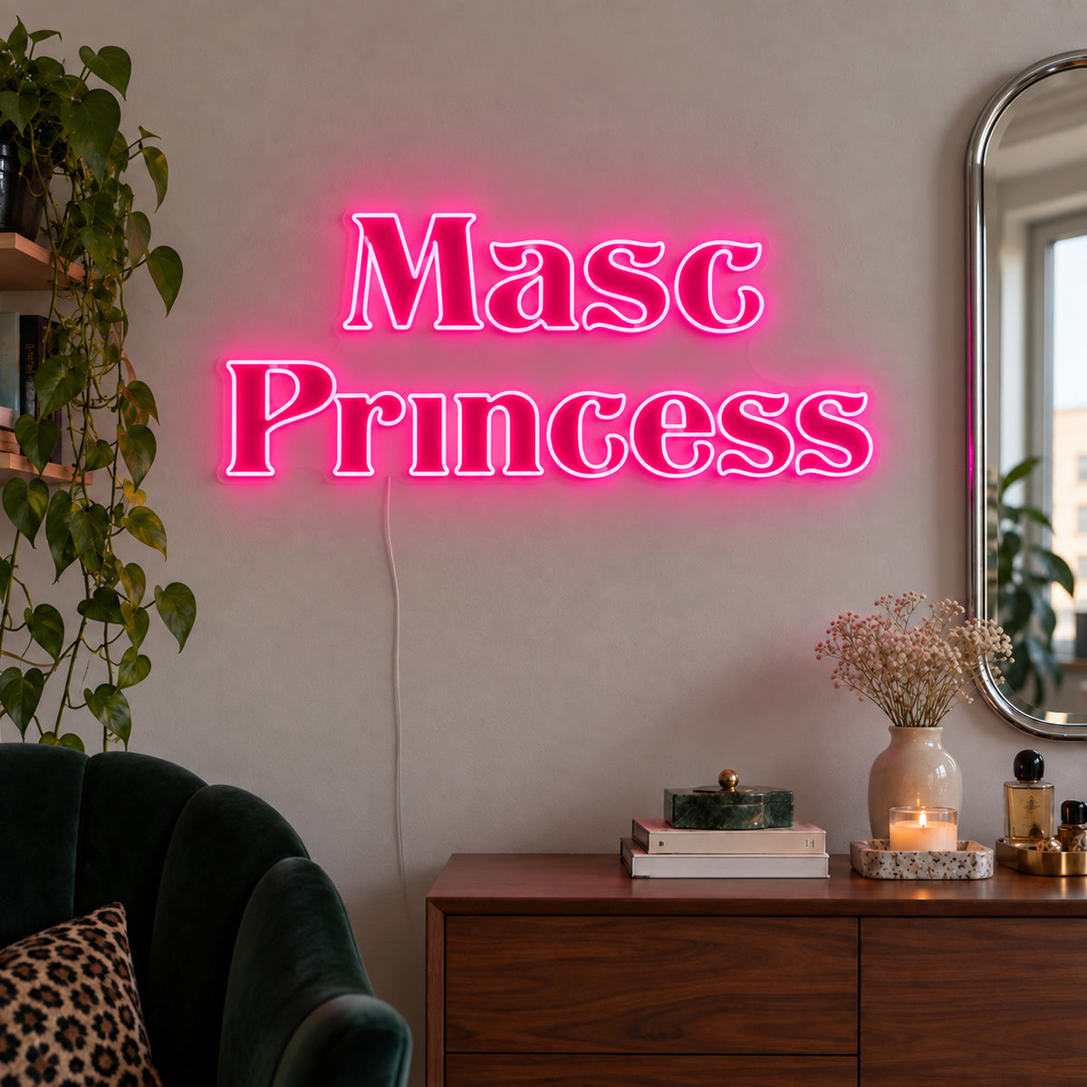 Rose Red version of the Masc Princess Neon Sign, shown above a wooden sideboard beside a green chair.