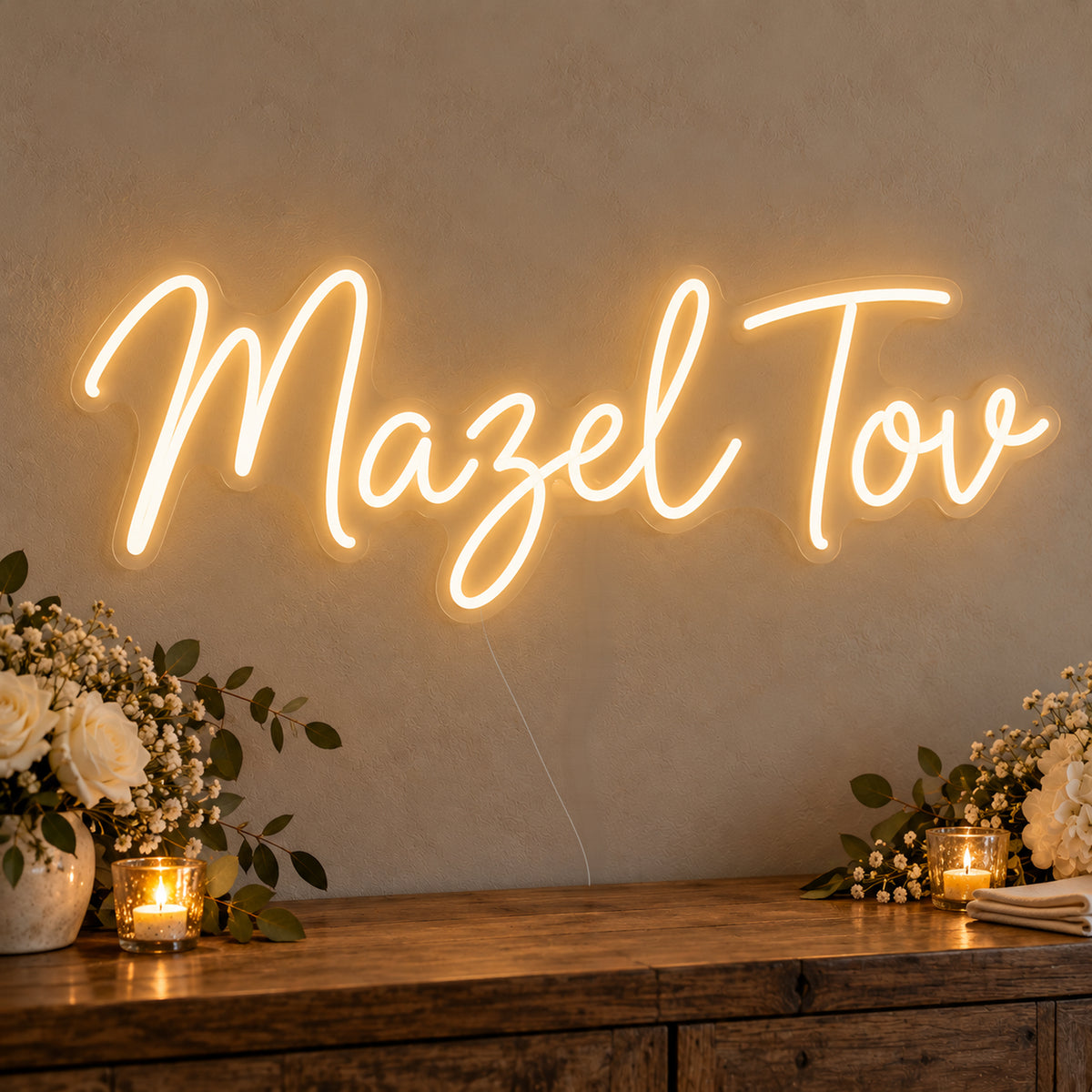 Mazel Tov Neon Sign on clear cut-to-shape acrylic, illuminated on a wall in a styled celebration setting