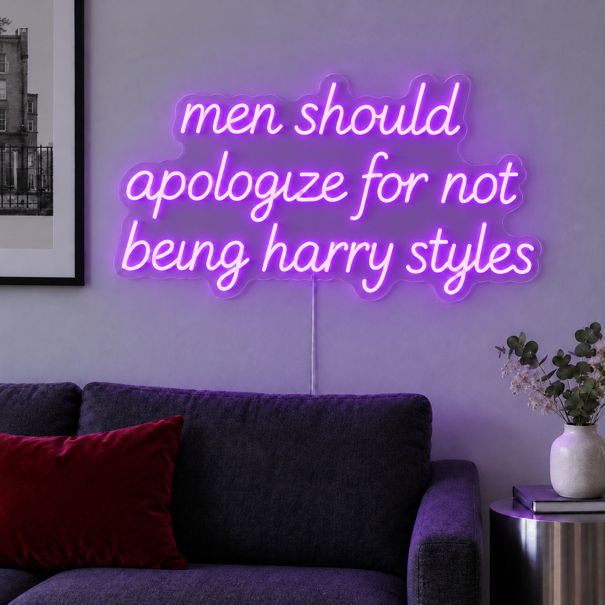 Men Should Apologize For Not Being Harry Styles Neon Sign with purple lighting, displayed above a dark sofa.