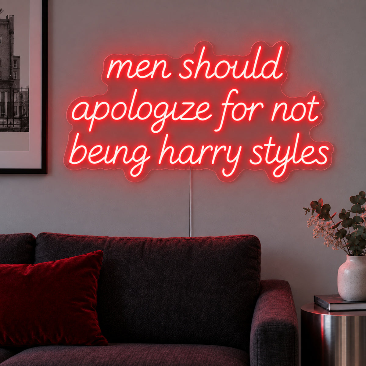 Men Should Apologize For Not Being Harry Styles Neon Sign with red lighting, displayed above a dark sofa.