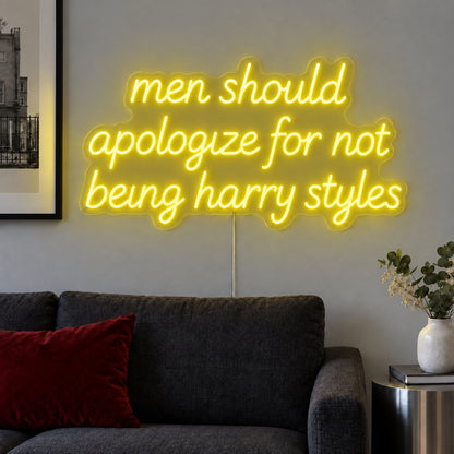 Men Should Apologize For Not Being Harry Styles Neon Sign with yellow lighting, displayed above a dark sofa.