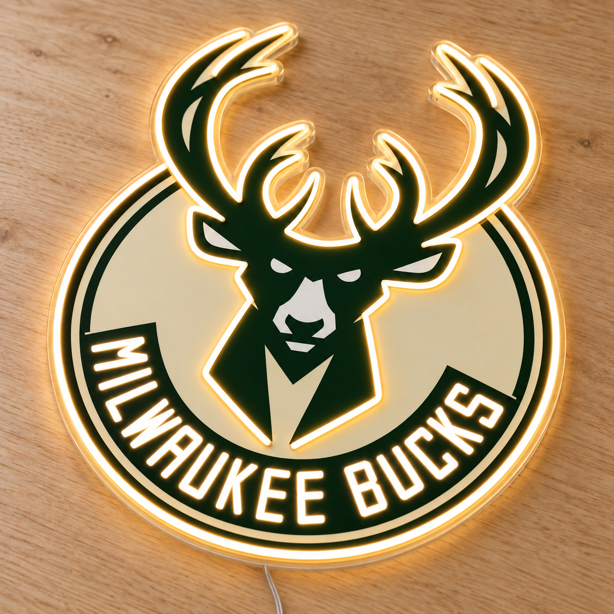 Angled Milwaukee Bucks LED neon sign on a wooden surface, with warm white deer and antler outlines, green and cream artwork and a thin wire routed behind the acrylic.