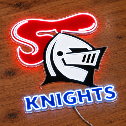 Newcastle Knights neon sign with a white UV printed helmet and illuminated outlines on clear acrylic, angled view on wood