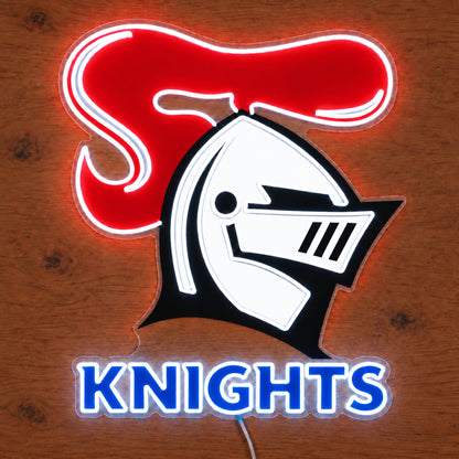 Newcastle Knights neon sign with a white UV printed helmet, red plume and blue lettering, front view on wood