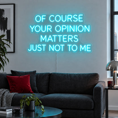 Ice Blue version of the Of Course Your Opinion Matters Just Not To Me Neon Sign, shown above a black sofa.