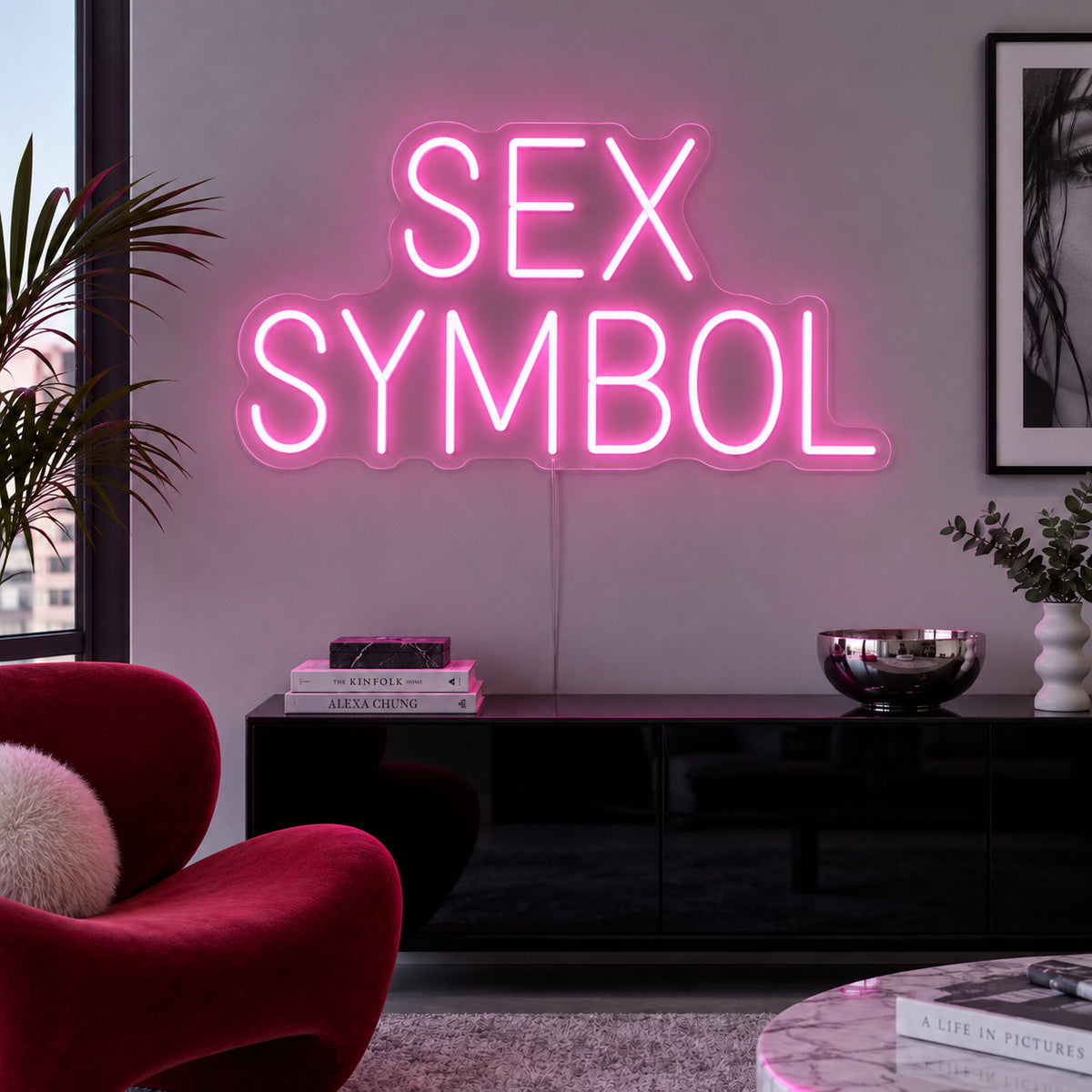 Sex Symbol Neon Sign glowing pink above a black sideboard.