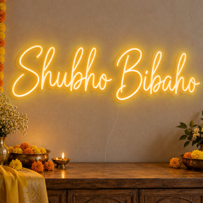 Shubho Bibaho Neon Sign in gold LED neon on clear acrylic, angled view