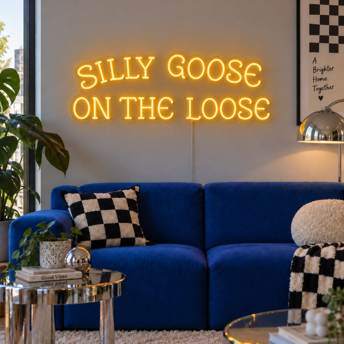 Silly Goose On The Loose Neon Sign glowing gold above a blue sofa with checkered cushions.