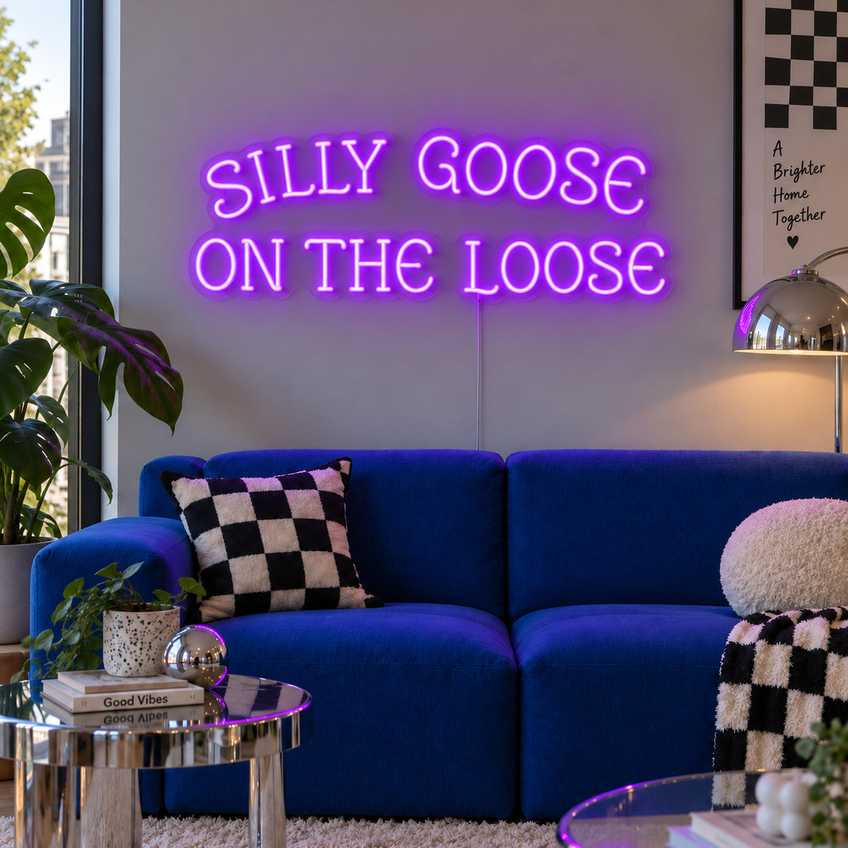 Silly Goose On The Loose Neon Sign with purple lighting, displayed above a blue sofa with checkered cushions.