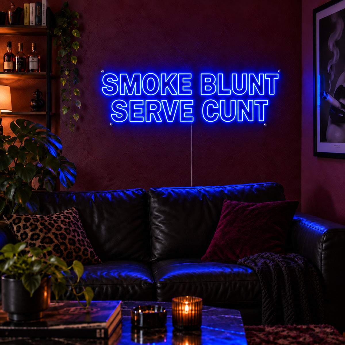 Smoke Blunt Serve Cunt Neon Sign glowing blue above a black leather sofa.