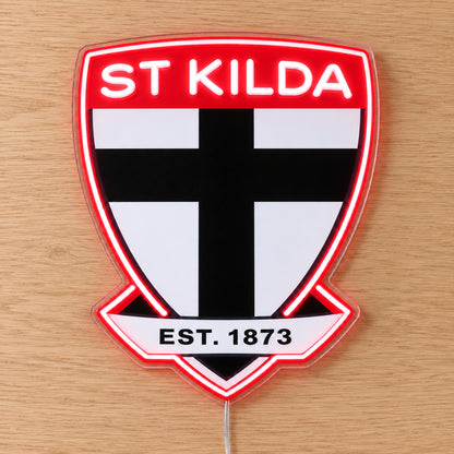St Kilda Saints Neon Sign with white neon lettering and red outline, lying flat on light wood