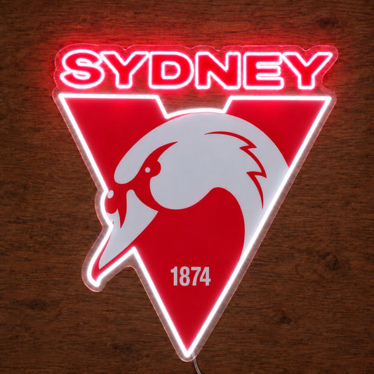 Sydney Swans neon sign glowing brightly on a wooden surface in dim lighting